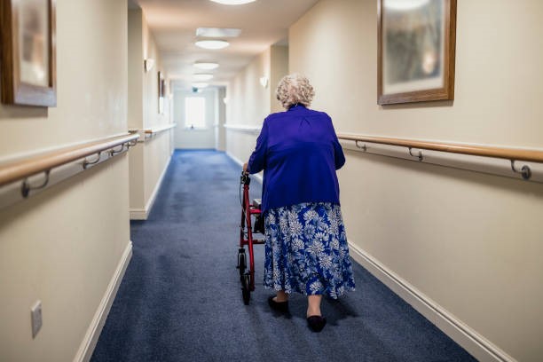 Visuel d'une personne âgée se déplaçant dans un corridor avec un déambulateur