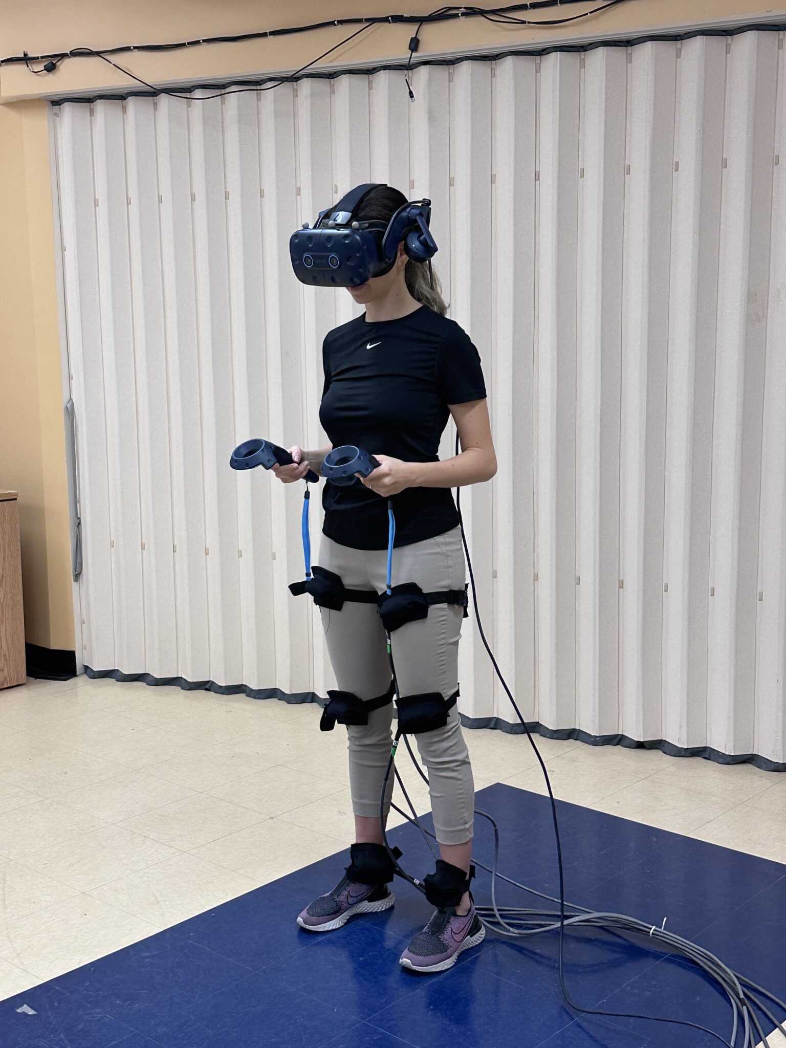 Personne utilisant un dispositif de réalité virtuelle avec stimulation par vibrations pour un entraînement de la marche en position debout.