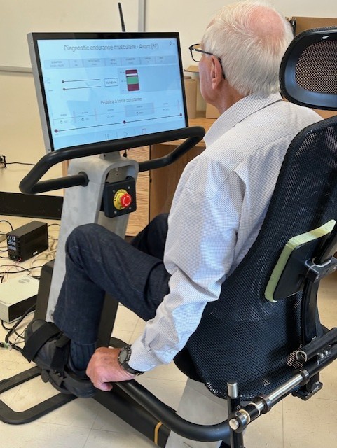 Personne utilisant un vélo intelligent pour un entraînement des membres inférieurs en position assise.